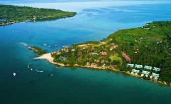 a bird 's eye view of a coastal area with houses , trees , and boats on the water at Badian Island Wellness Resort