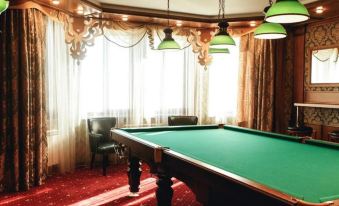 a large pool table is in the middle of a room with red carpet and green lamps at Luxe