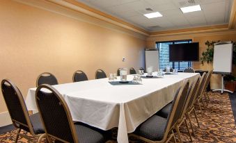 a large conference room with a long table covered in a white tablecloth , several chairs , and a tv mounted on the wall at Grand Hotel at Bridgeport