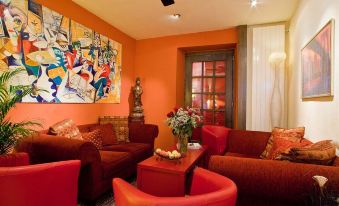 a living room with red and orange color scheme , including a couch , chairs , and paintings at Hotel Admiral