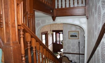 a wooden staircase with a curved railing leads to a living room with arched doorways at The Gables