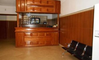 a wooden reception desk with a clear top and two black chairs in front of it at Hibis Hotel