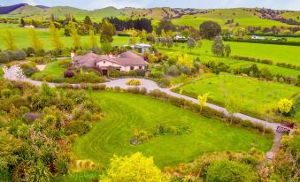 aerial view of a large green field with a house in the background , surrounded by trees and hills at The Summit Lodge