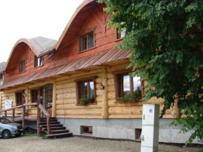 a large wooden house with a curved roof and three windows is surrounded by trees at Troll