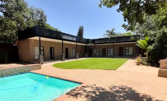 a large brick house with a swimming pool in the backyard , surrounded by trees and grass at Copperwood Hotel and Conferencing