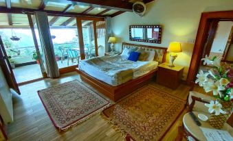 a spacious bedroom with a large bed , two chairs , and a window overlooking a balcony at Lockwood Hotel Murree