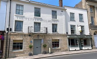 "a white building with a sign that reads "" the peppermill hotel "" is situated on a street corner" at The Peppermill Town House Hotel & Restaurant