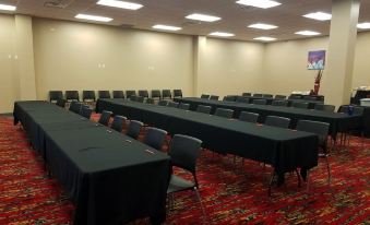 a conference room with rows of black tables and chairs , a large screen on the wall , and a poster on the wall at Shoshone Rose Casino & Hotel