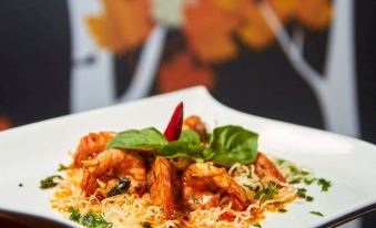 a white plate with a seafood dish garnished with green leaves and a red pepper at Metland Hotel Bekasi