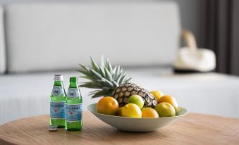 "a bowl of fruit is placed on a wooden table next to two bottles of the brand "" heineken "" on a white background" at Abode Malua Bay