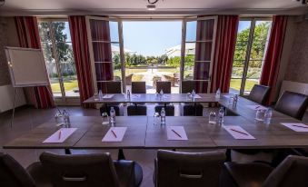 a large dining room with multiple tables and chairs arranged for a meeting or event at Hôtel la Ramade