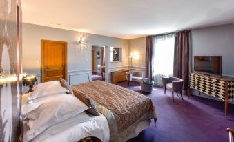a luxurious hotel room with a king - sized bed , a flat - screen tv , and a dining table at Hôtel Golf Château de Chailly