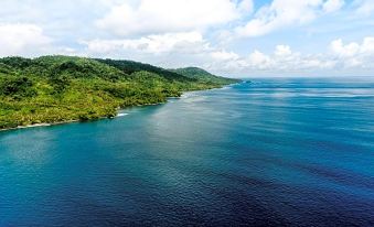 aerial view of a large body of water , possibly an ocean or a lake , surrounded by lush green hills and mountains at Moro Ma Doto