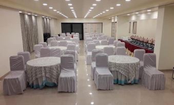 a large , empty banquet hall with white tables and chairs set up for an event at Aroma