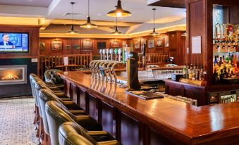 a bar with multiple beer taps and a row of chairs in front of it at Hillgrove Hotel, Leisure & Spa