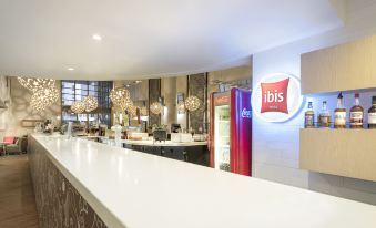 "a modern , well - lit kitchen with a large bar counter and a sign for "" ibis "" on the wall" at Ibis Melbourne Hotel and Apartments