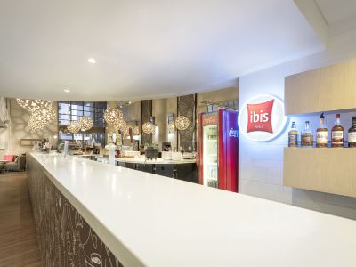 "a modern , well - lit kitchen with a large bar counter and a sign for "" ibis "" on the wall" at Ibis Melbourne Hotel and Apartments