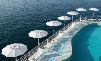 a large swimming pool with umbrellas and boats in the water , surrounded by a deck and surrounding landscape at Hotel Miramalfi