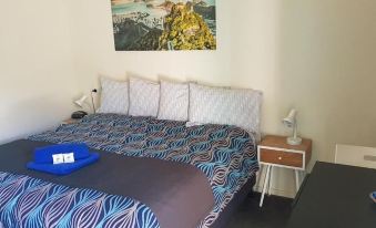 a bed with a blue and white patterned comforter , two pillows , and a lamp on the nightstand at Kadina Village Motel