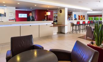 a modern hotel lobby with a large reception desk , comfortable seating , and a bartender at the counter at Holiday Inn Express East Midlands Airport