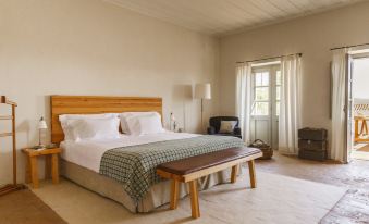 a large bed with a wooden headboard and footboard is in a room with white walls at São Lourenço do Barrocal