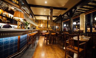 a dimly lit , wooden bar with a counter and stools , surrounded by bottles and glasses at The Blue Boar