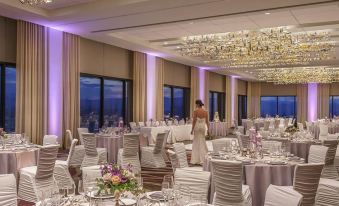 a woman in a white dress standing in a large dining room , surrounded by tables and chairs at Grand Hyatt Denver