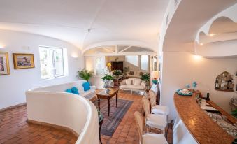 a spacious living room with white walls , wooden floors , and a curved ceiling , connected to a dining area at Covo dei Saraceni