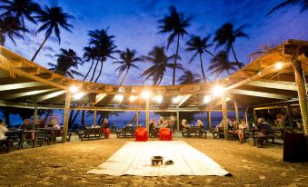 a group of people gathered on a sandy beach , enjoying the evening atmosphere under a covered area at Likuri Island Resort Fiji