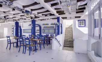 a modern , minimalist restaurant with white walls and blue accents , featuring a dining area with blue chairs and tables at Vitalis Villas