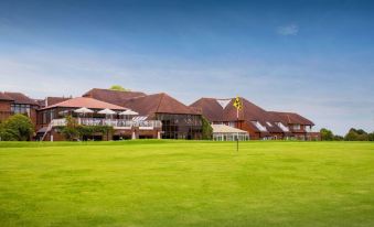 a large building with a green lawn in front of it and a yellow flower in the foreground at Dale Hill Hotel