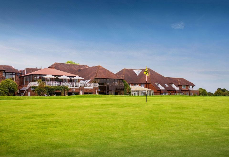 a large building with a green lawn in front of it and a yellow flower in the foreground at Dale Hill Hotel