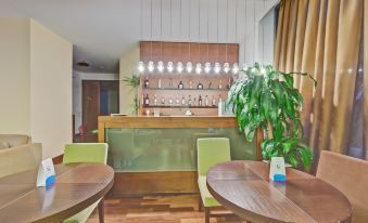 a room with a wooden bar and chairs , featuring green chairs around a dining table at Marin Hotel