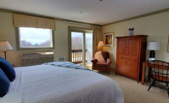 a bedroom with a large bed , a chair , and a door leading to a balcony at Atkinson Resort & Country Club