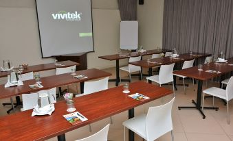 "a conference room with rows of tables and chairs , a projector screen displaying the brand name "" vivitek .""." at Balmoral Lodge