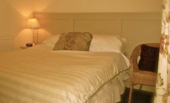 a well - lit bedroom with a white bed , a chair , and a lamp on the nightstand at The Midland Hotel