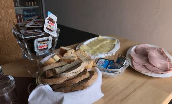 a dining table with a variety of food items , including bread , cheese , ham , and other snacks at Blue Eagle Guesthouse