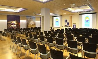 a large conference room with rows of chairs arranged in front of a projector screen at Invisa Hotel Club Cala Blanca