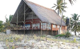 a beach house with a thatched roof and wooden deck is surrounded by palm trees at White Sands
