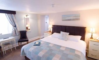 a well - lit hotel room with a large bed , a chair , and a window with curtains at Ellerby Country Inn