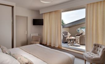 a bedroom with a bed , chair , and sliding glass door leading to an outdoor patio at Hôtel la Ramade