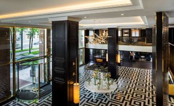 a modern hotel lobby with black and white patterned floor , a large chandelier hanging from the ceiling , and two people walking through the lobby at Hilton Vienna Plaza