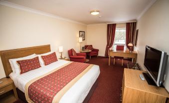 a hotel room with a king - sized bed , a desk , a chair , and a television . also a dining table in the room at Eastwood Hall