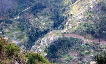 a picturesque village nestled in a valley surrounded by lush greenery , with a winding road leading up to it at Eira do Serrado - Hotel & Spa