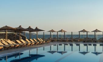 a large outdoor swimming pool surrounded by lounge chairs and umbrellas , providing a relaxing atmosphere at Civitel Creta Beach