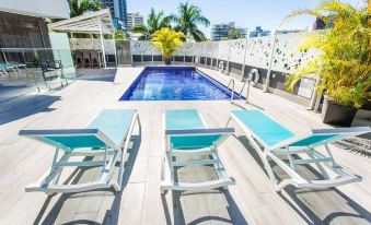 a rooftop deck with a swimming pool surrounded by lounge chairs and a wooden deck at Mercure Brisbane Spring Hill
