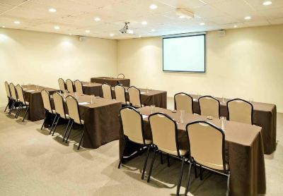 a conference room with chairs arranged in rows and a projector screen on the wall at Ibis Melbourne Hotel and Apartments