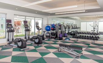 a well - equipped gym with various exercise equipment , including treadmills and weight machines , on a green and white checkered floor at Element Chelmsford