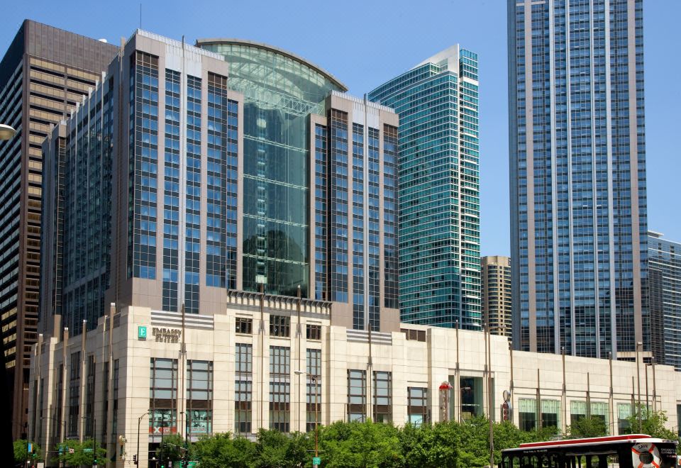 a modern building with a curved glass facade , surrounded by modern skyscrapers and trees at Embassy Suites by Hilton Chicago Downtown Magnificent Mile