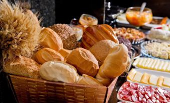 a variety of bread rolls and pastries displayed in a basket on a dining table at North Hotel - Aeroporto